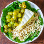 bowl with spinach grilled grapes brie cheese and slivered almonds