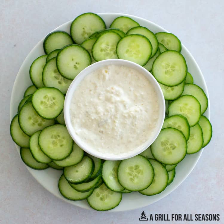 smoked onion dip in a bowl surrounded by sliced cucumbers