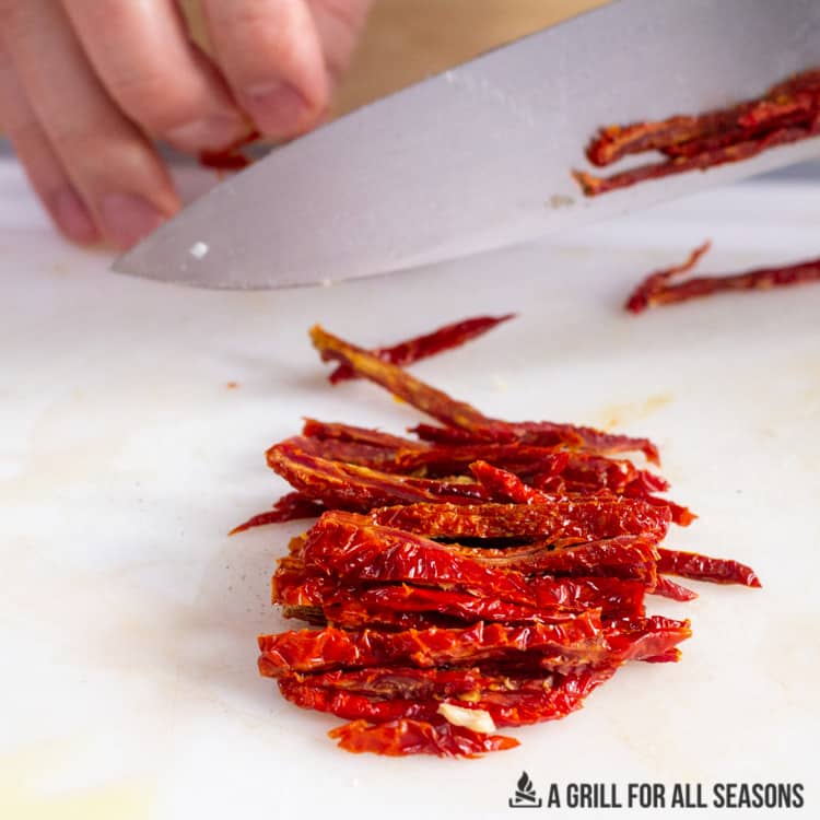 hands cutting sundried tomatoes