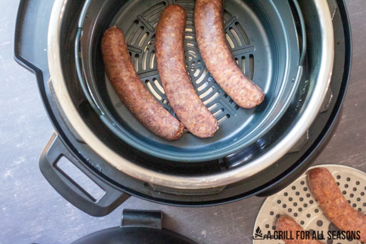 air fryer basket with raw sausages