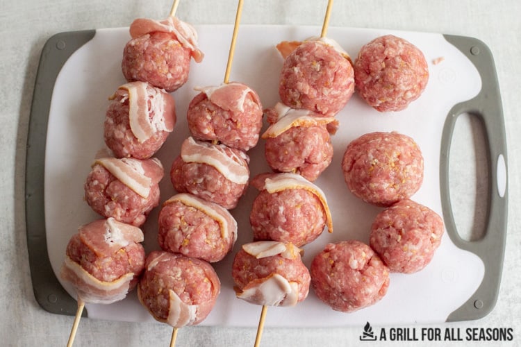 16 ground pork meatballs on skewers with small slices of bacon in between each one