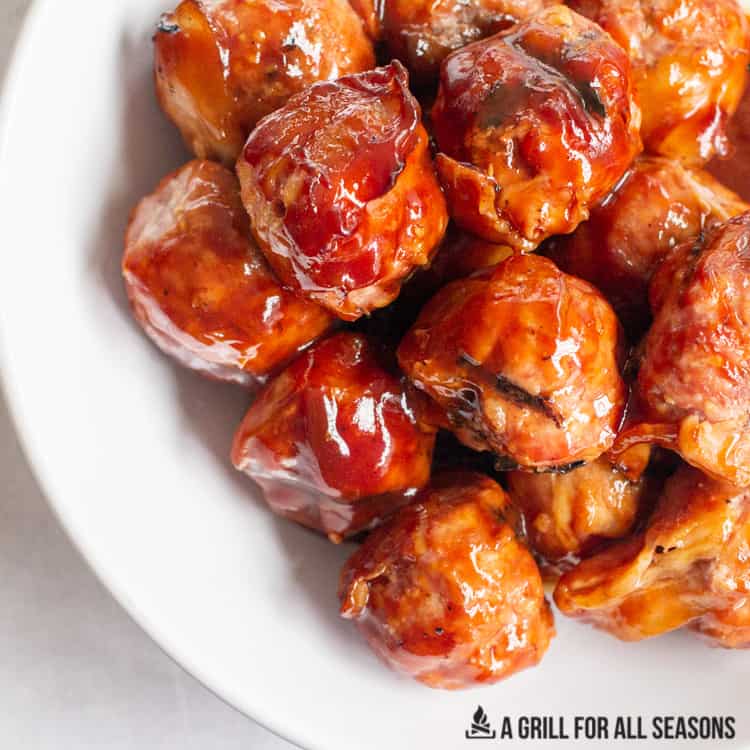 plate of smoked meatballs wrapped with bacon drizzled with barbecue sauce