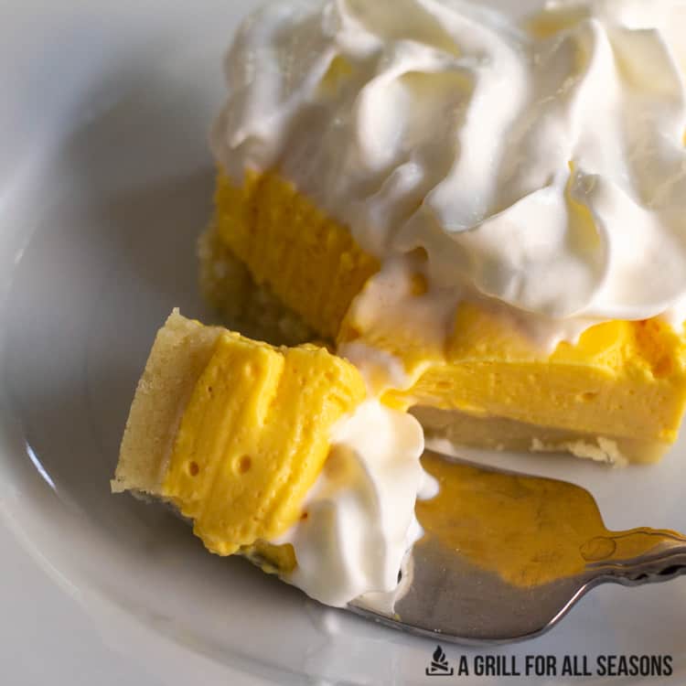 one of the No Bake Mango Cheesecake Bars on a plate with a bite on a fork