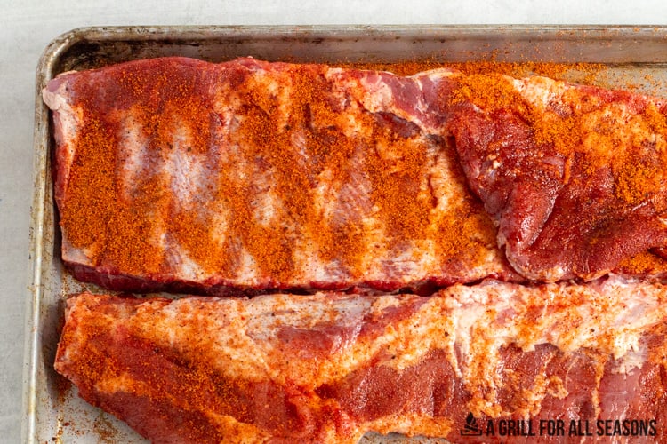raw pork ribs on a tray with seasoning rub