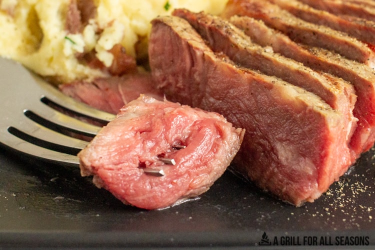 close up of rare sliced steak on a fork