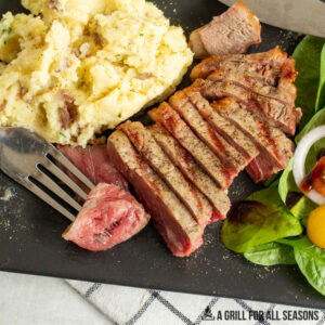 sliced pellet grill steak on plate with sides