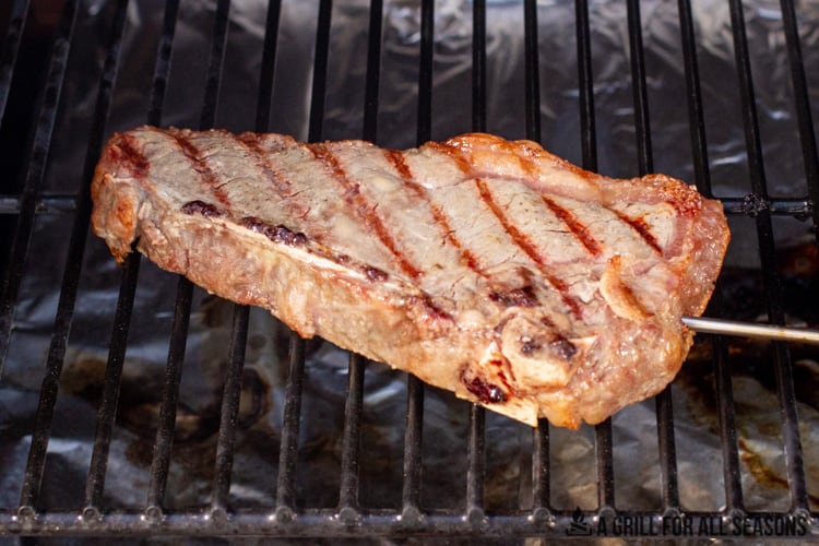 steak cooking on pellet grill with a temperature probe in the center