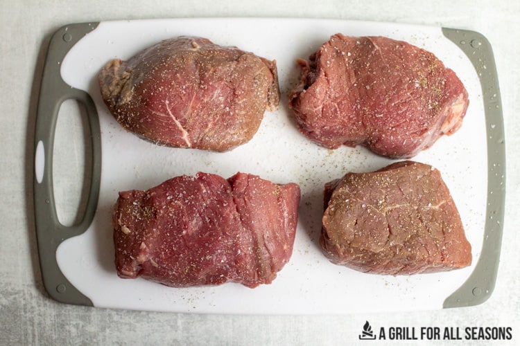 four sirloin steaks on a cutting board