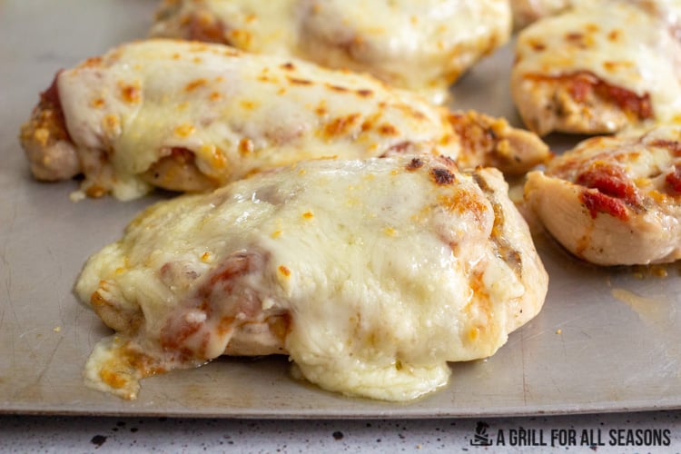 several pieces of grilled chicken parm on cooking tray