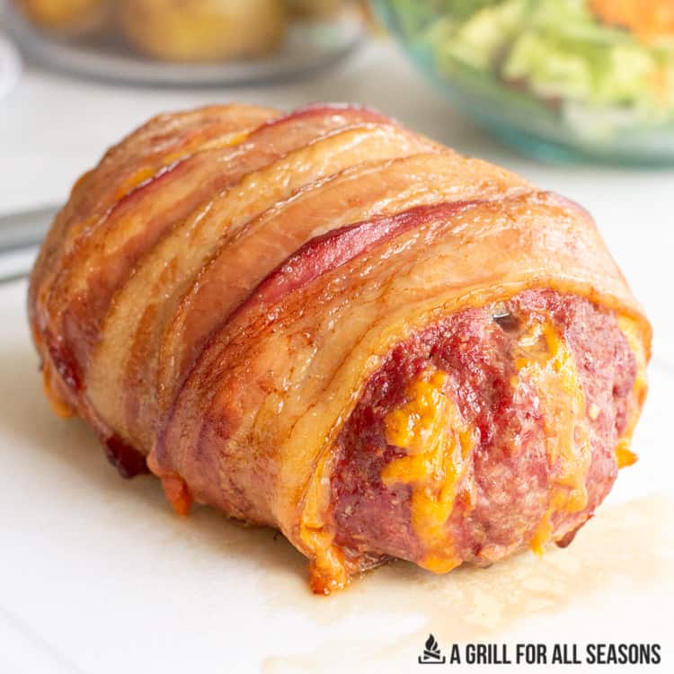smoked meatloaf wrapped in bacon resting on cutting board