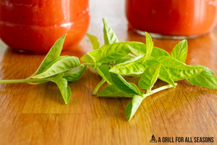 jars of smoked tomato sauce with fresh basil leaves on table