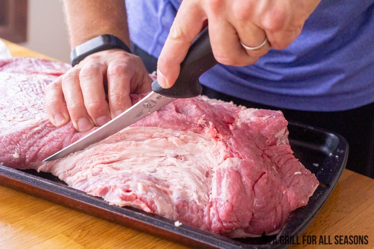 whole brisket being trimmed of excess fat.