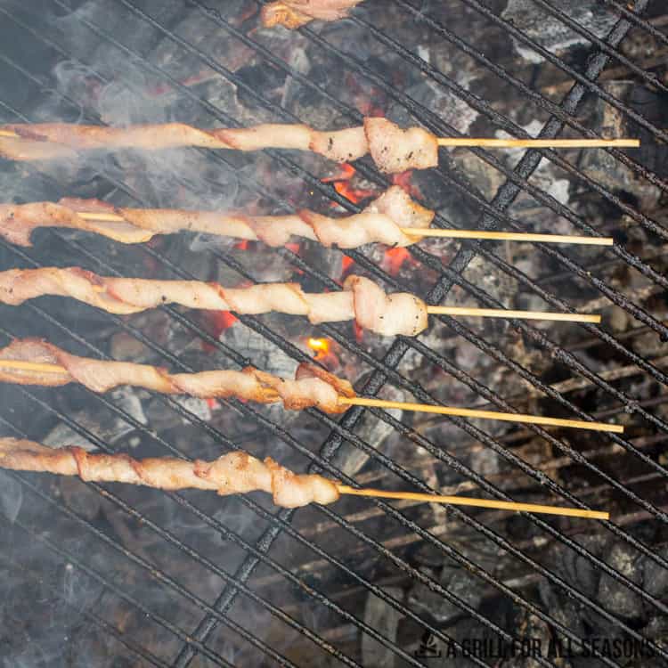 Bacon skewers cooking on grill.