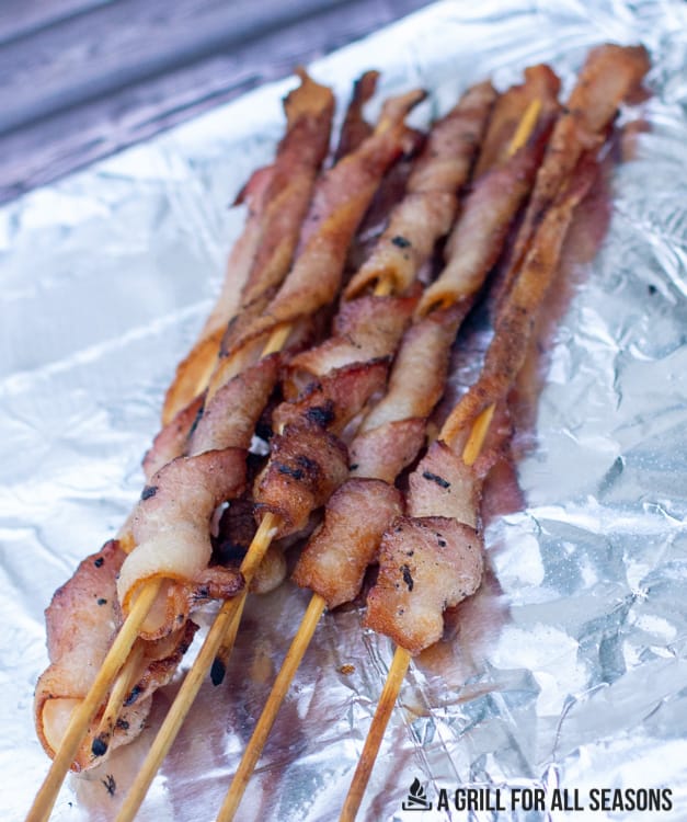 Bacon on a stick cooked and sitting on foil.