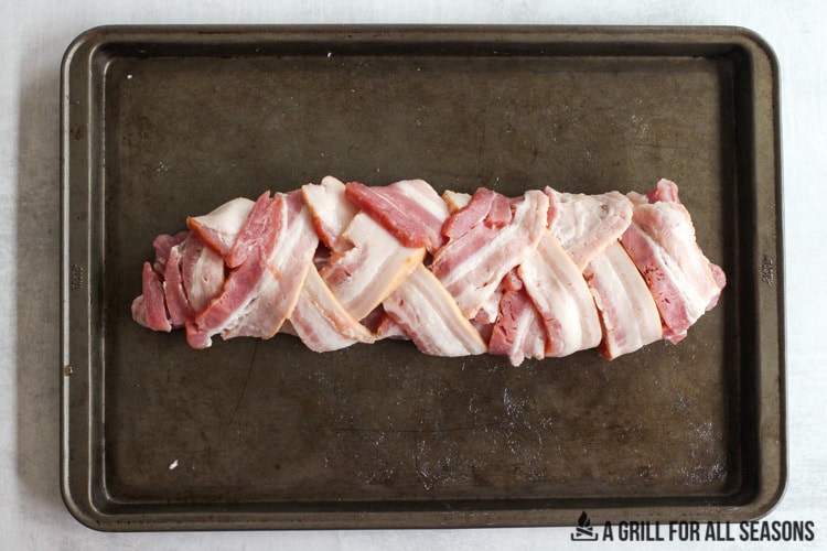 bacon crisscrossed around the meat on cooking sheet.