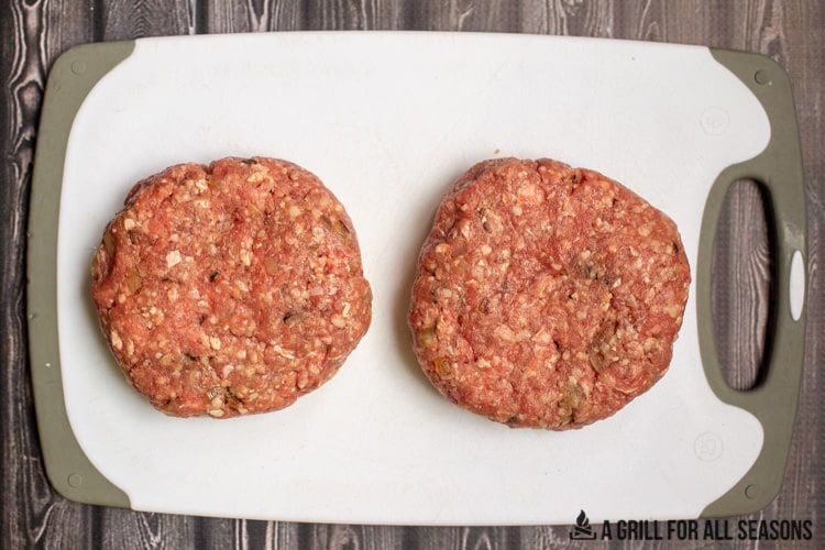 Two eight ounce beef patties on cutting board.