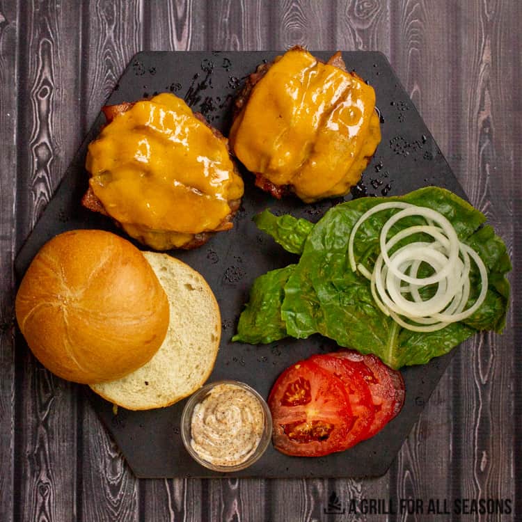 smoked burgers, bun, and toppings on cutting board