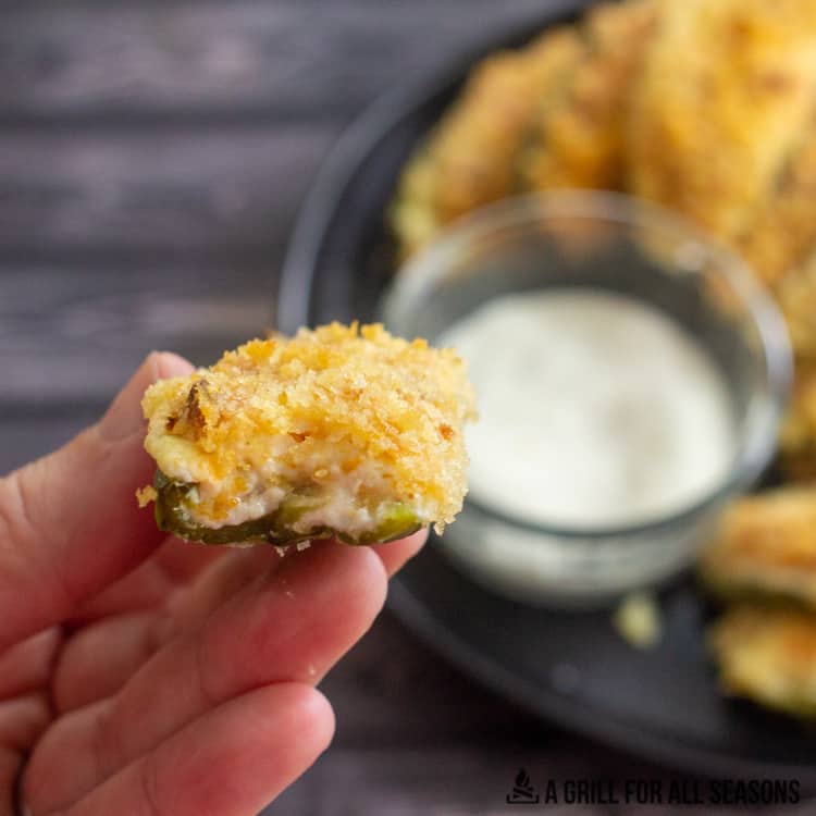 Smoked jalapeno poppers on plate with ranch dressing for dipping with one being eaten.