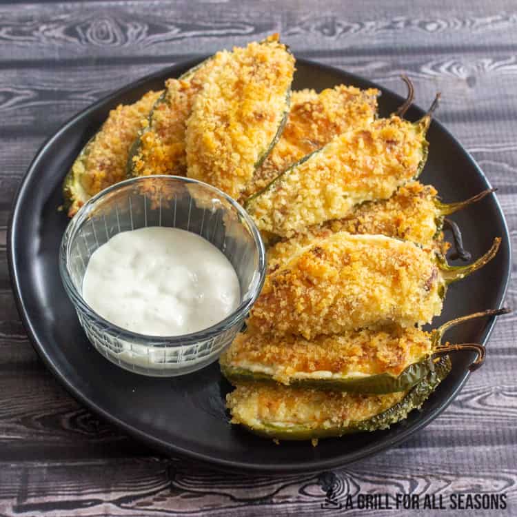 Smoked jalapeno poppers on plate with ranch dressing for dipping.