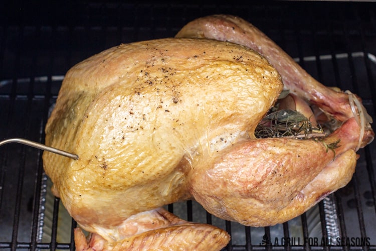 Smoked turkey in smoker with thermometer probe.