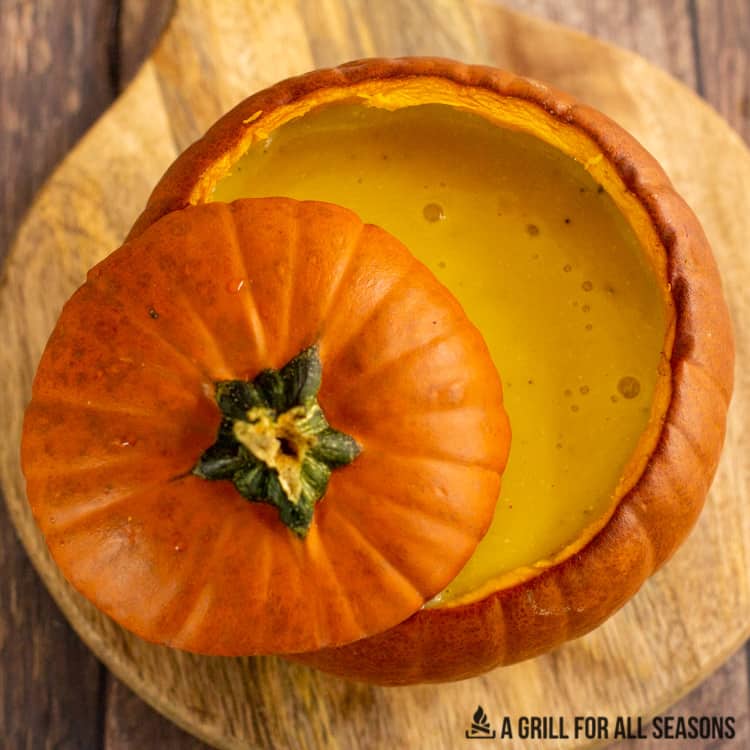 Pumpkin filled with smoked pumpkin soup with top of pumpkin lid.