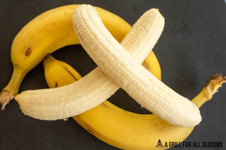 two peeled bananas and two bananas in skin