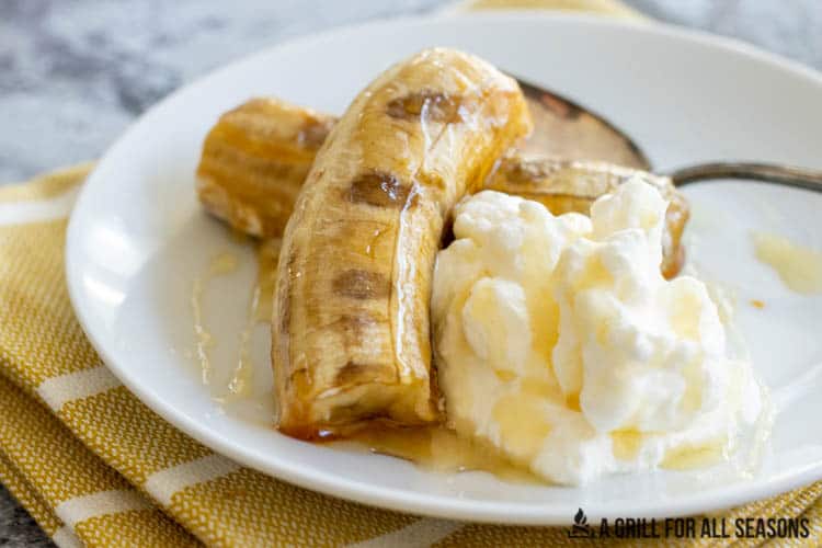 halved banana on plate with whipped cream and caramel