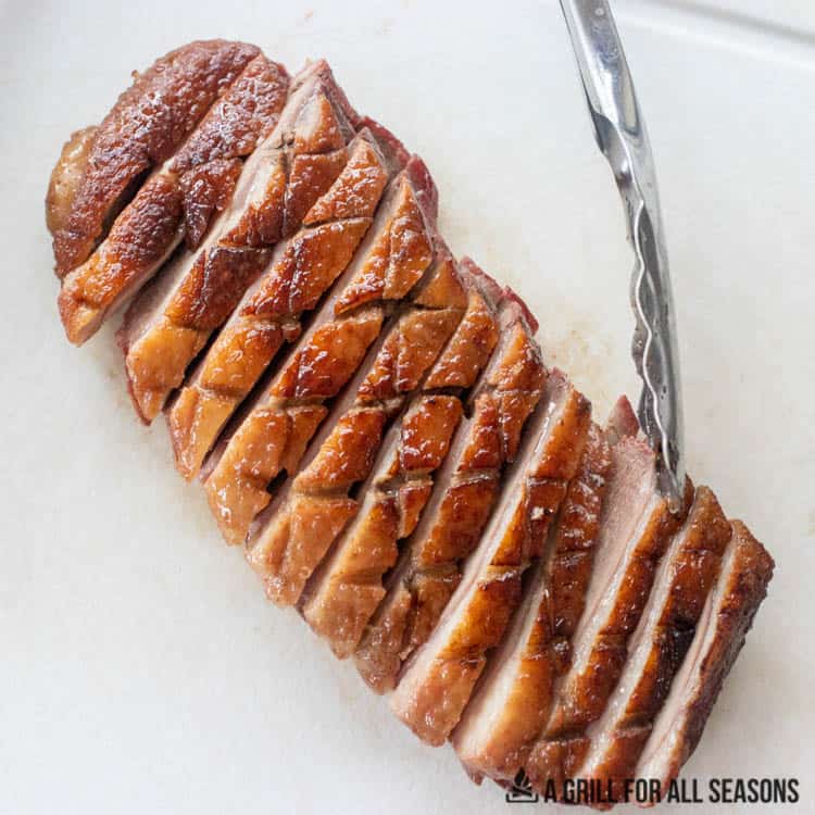 Sliced smoked duck breast on a cutting board.