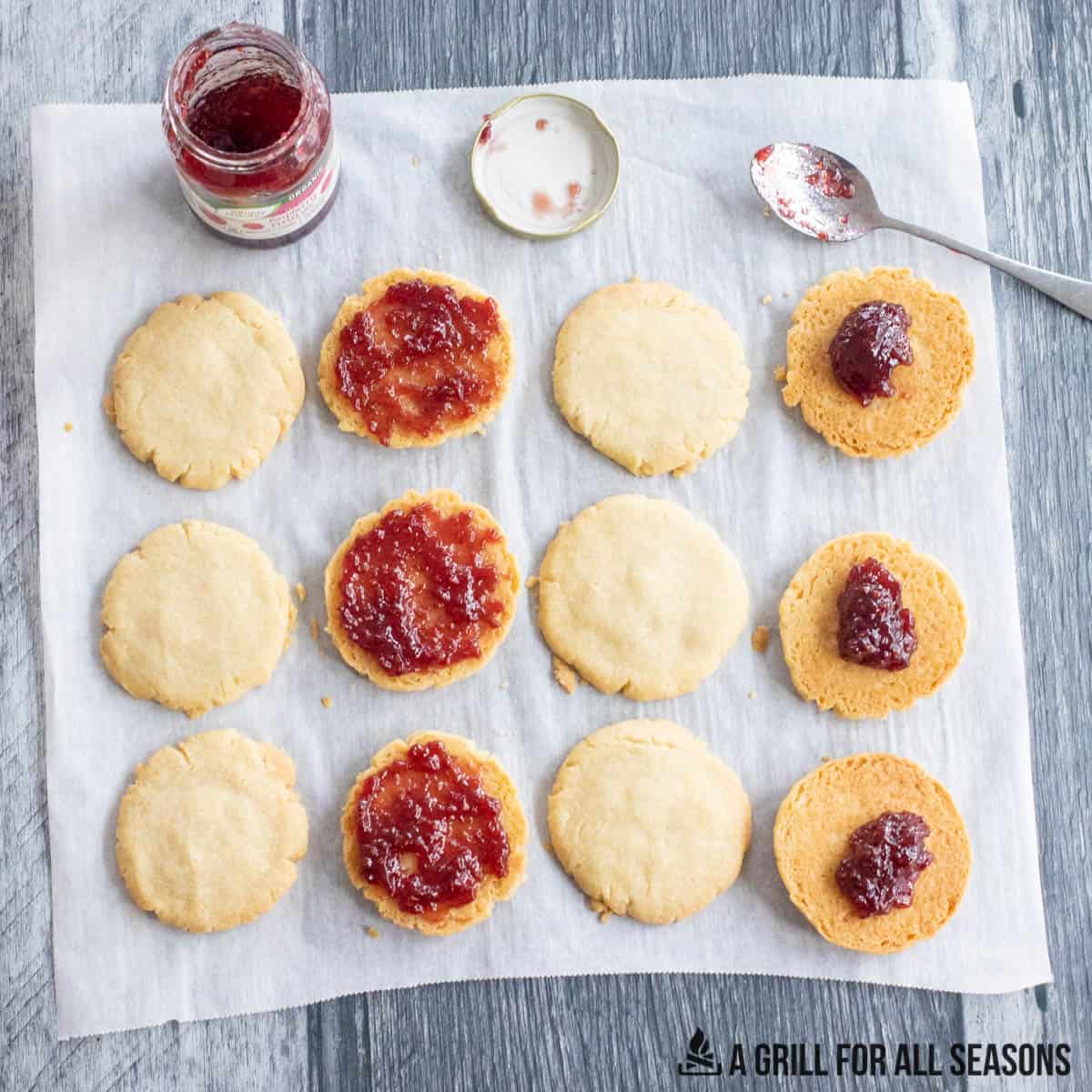 cookies upside down being spread with raspberry jam