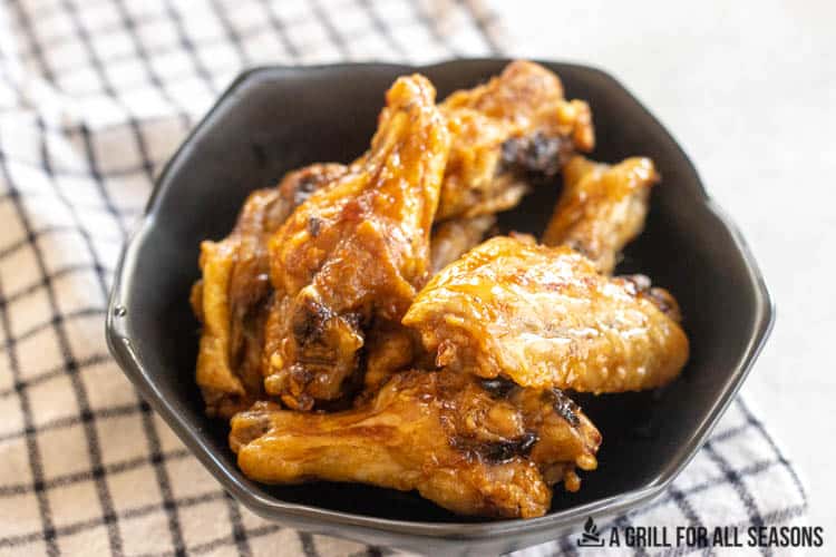 air fryer frozen wings cooked and in bowl with sauce