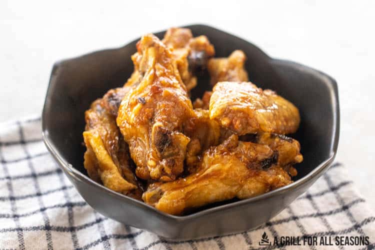 air fryer frozen chicken wings cooked and in bowl with sauce