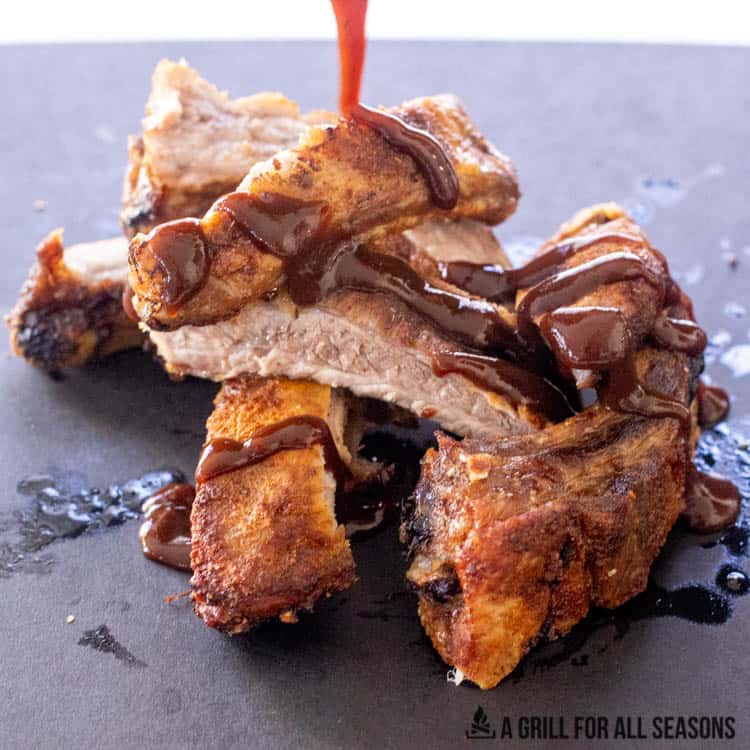 sauce being drizzled on pork ribs
