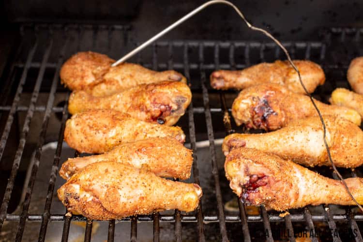 chicken legs on smoker grate with thermometer