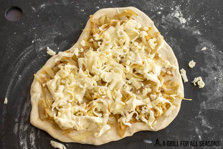pizza dough topped with onions, brie, and mozzarella