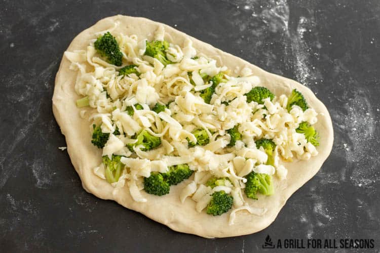 pizza dough topped with broccoli and cheese