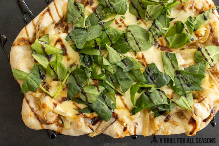 smoked pizza topped with onions, brie, spinach, and balsamic