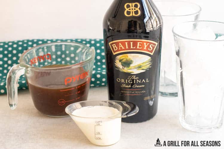 ingredients in small measuring cups with a bottle of irish cream behind