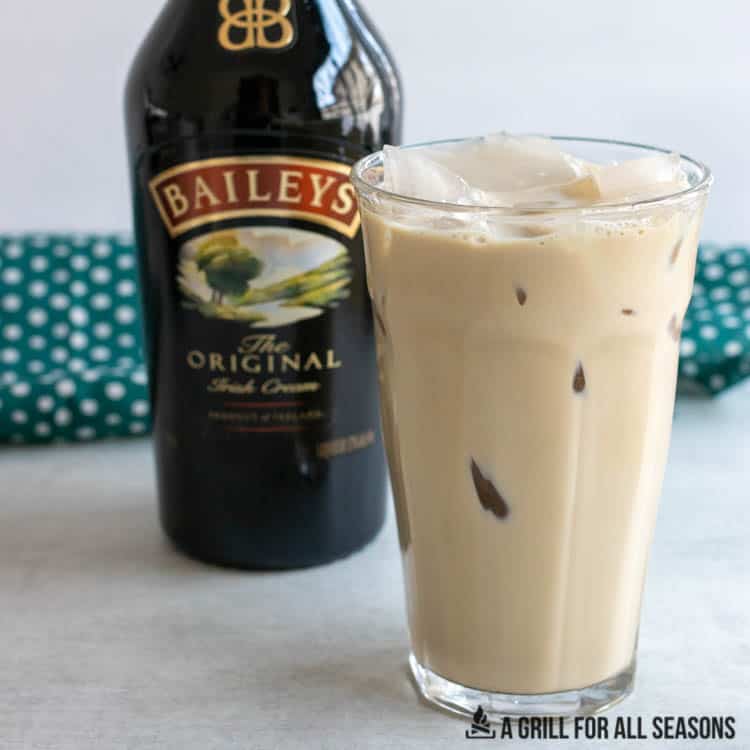 glass of bailey's iced coffee with a bottle of irish cream behind