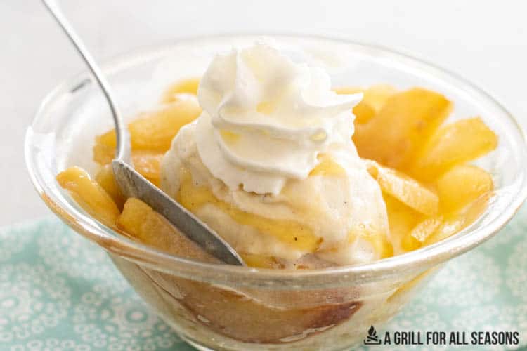 close up of spoon with bite of stewed pears with ice cream, honey, and whipped cream