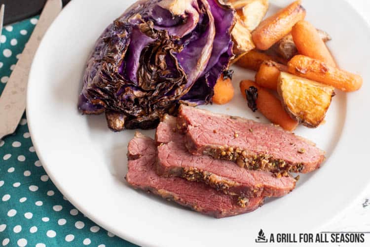 close up of slices of smoked corned beef on a plate with cabbage potatoes and carrots