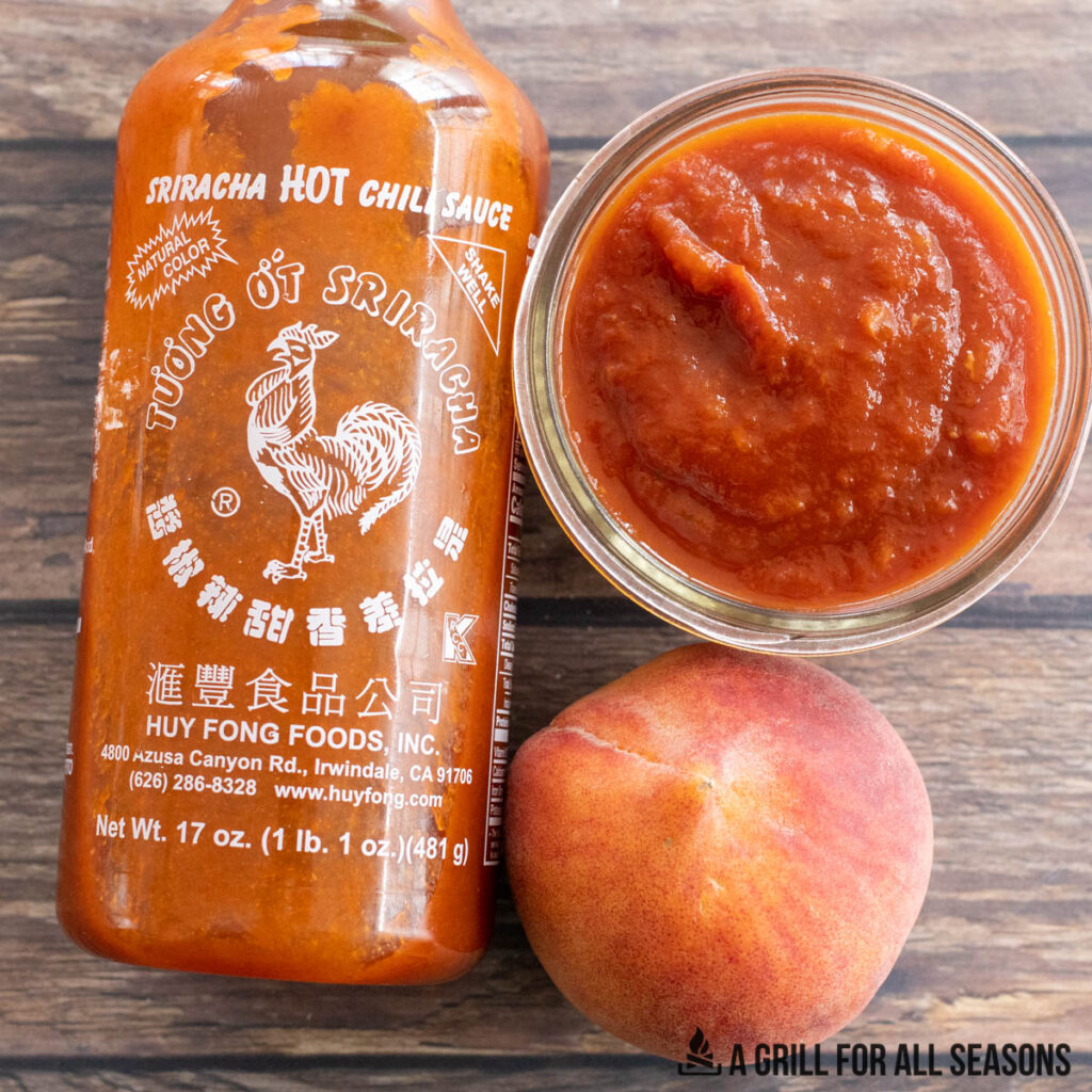 bottle of sriracha and fresh peach next to jar of sauce