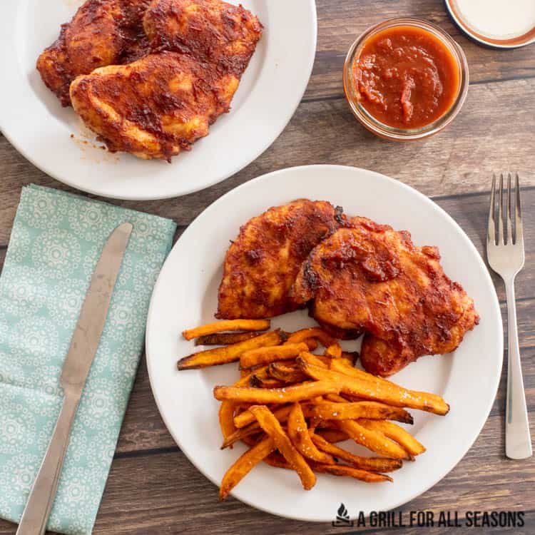 how to smoke chicken thighs served on a plate with sweet potato fries