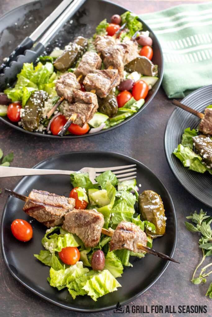 greek steak salad on platter and small plates