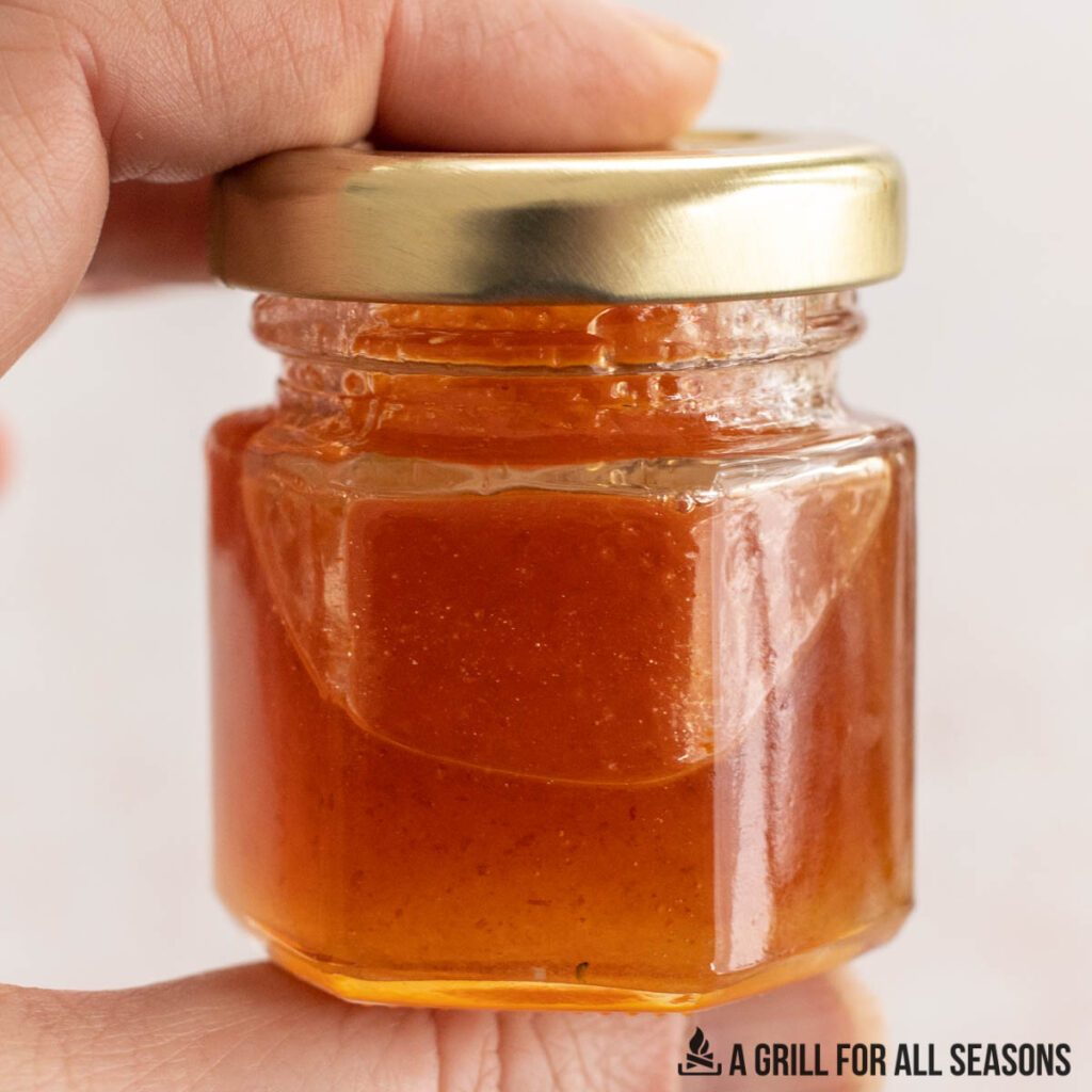 hand holding small jar of honey sriracha sauce