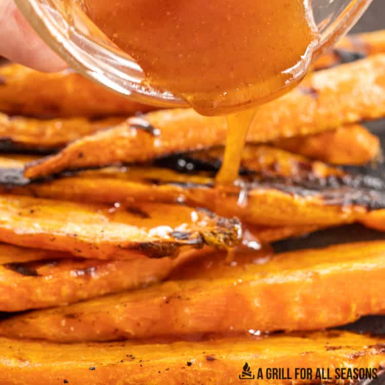 honey sriracha sauce being drizzled on grilled carrots