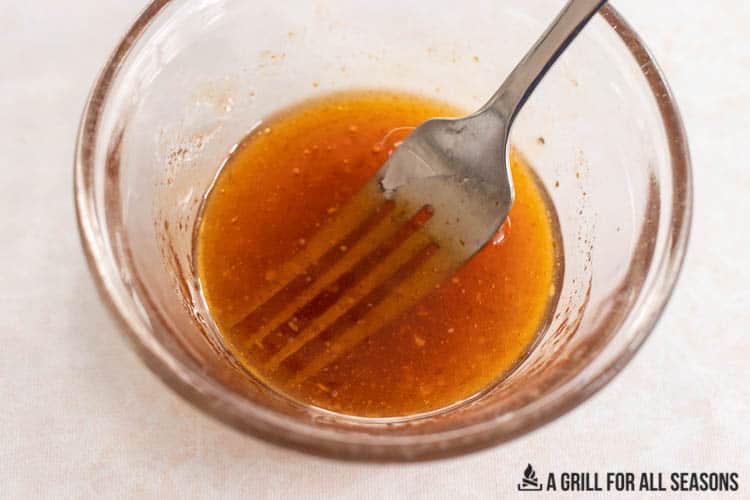 small bowl of honey sriracha sauce being mixed with a fork