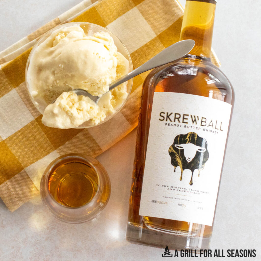 overhead shot of bottle of skrewball whiskey next to glass of whiskey and bowl of skrewball whiskey ice cream