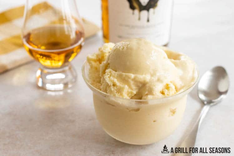 small bowl of skrewball whiskey ice cream with bottle of whiskey behind