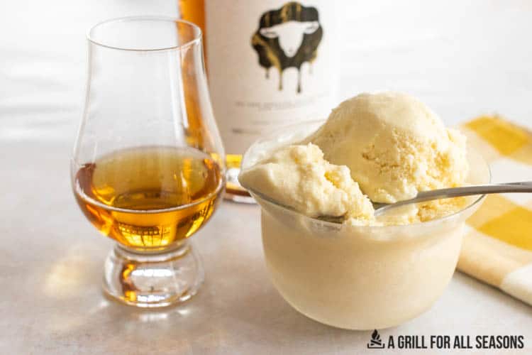 bowl of skrewball whiskey ice cream next to a glass of whiskey
