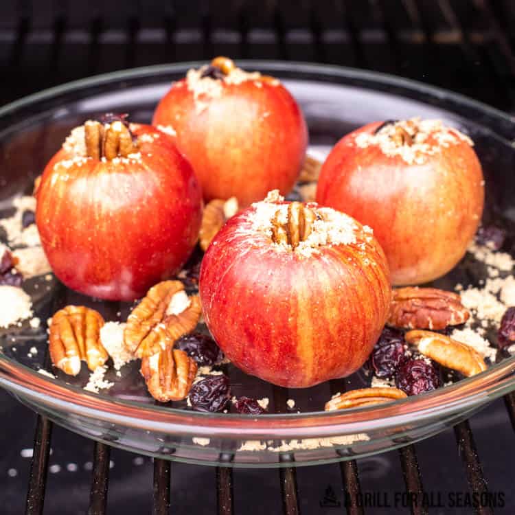 cored apples in glass pie plate on smoker